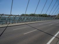 a truck driving across a bridge near a street corner near buildings and a bridge with many cables