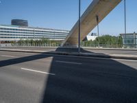 a truck driving across a bridge near a street corner near buildings and a bridge with many cables