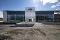 the ford dealership is empty on a sunny day with no people standing outside it