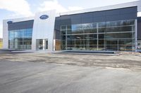 the exterior of a ford dealership with its doors open and trees reflected in windows