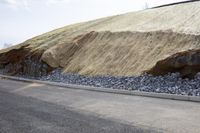 a dirt and rock barrier separates a roadway and hillside in the process of being built