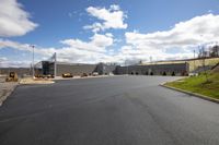 this is a large empty parking lot near the building and green grass on a sunny day