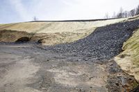 a very dirty and dirted road next to a hill with a slope behind it