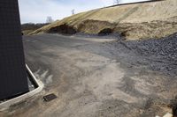 a road that has a dump on the side near a hill with no cars driving