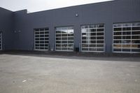 a warehouse with lots of garage doors and windows with a fire hydrant outside in front