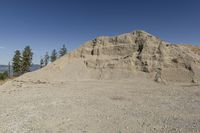 there is a bike rider on a paved dirt road through rocky area near a mountain