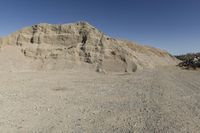 there is a bike rider on a paved dirt road through rocky area near a mountain