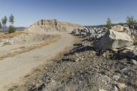 there is a bike rider on a paved dirt road through rocky area near a mountain