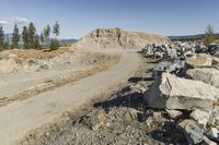 there is a bike rider on a paved dirt road through rocky area near a mountain