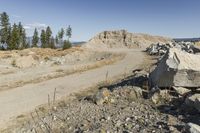 there is a bike rider on a paved dirt road through rocky area near a mountain