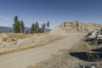 there is a bike rider on a paved dirt road through rocky area near a mountain