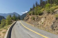 a road leading down to some trees and mountains in the distance with one lane on one side and no other on it