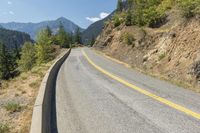 a road leading down to some trees and mountains in the distance with one lane on one side and no other on it