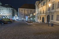 the street in front of a building is empty and cobblestone at night time