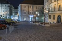 the street in front of a building is empty and cobblestone at night time