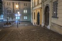 the street in front of a building is empty and cobblestone at night time