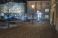 the street in front of a building is empty and cobblestone at night time