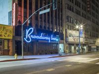 the neon sign of broadway in new york is lit up at night by a city traffic light