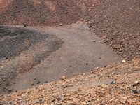 the area where there is red rocks and gravel on the ground and the road is marked with a black dot