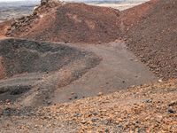 the area where there is red rocks and gravel on the ground and the road is marked with a black dot