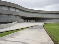 a building with cement roof near green grass and lawn in front of it, under a gray sky