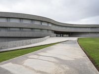 a building with cement roof near green grass and lawn in front of it, under a gray sky