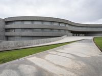 a building with cement roof near green grass and lawn in front of it, under a gray sky