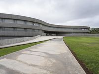 a building with cement roof near green grass and lawn in front of it, under a gray sky