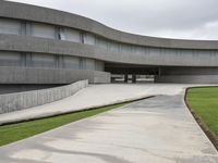 a building with cement roof near green grass and lawn in front of it, under a gray sky