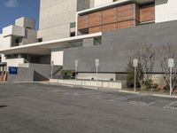 the building is made of concrete and brown wood panels with a black sign that says parking spots are