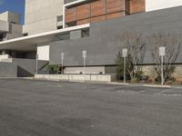 the building is made of concrete and brown wood panels with a black sign that says parking spots are