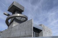 man in a white shirt is on a staircase near a large concrete structure with a very tall tower