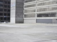 a skateboarder is riding through the parking garage of an empty building with columns
