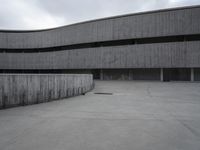 a building with cement roof near green grass and lawn in front of it, under a gray sky