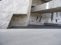 a skateboarder rides down a ramp near a building that looks like it is inside concrete