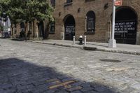 a street with brick and brick building next to a fire hydrant and a few trees