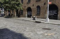 a street with brick and brick building next to a fire hydrant and a few trees