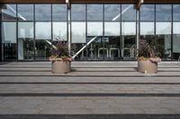 an empty front porch outside the building with planters on it near glass door doors