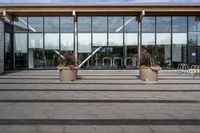 an empty front porch outside the building with planters on it near glass door doors