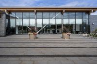 an empty front porch outside the building with planters on it near glass door doors