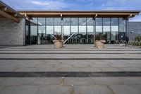 an empty front porch outside the building with planters on it near glass door doors