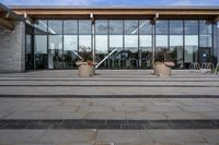 an empty front porch outside the building with planters on it near glass door doors