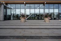 an empty front porch outside the building with planters on it near glass door doors