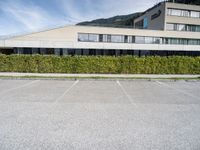 a building near a green hedge in the parking lot of a building in the mountains