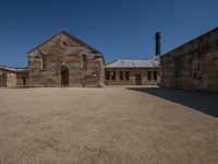 a large building with a circle in front of it on a gravel ground under a blue sky