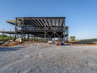 a picture of a building being built on a field near a forest in the background