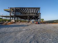 a picture of a building being built on a field near a forest in the background