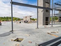 a large building under construction next to several empty benches on concrete floor space, blue sky and blue sky in background