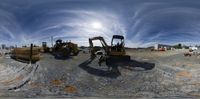 this is a photograph of several machines working on a building construction site with clouds in the sky above