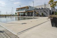 the woman is looking at the large building and pool area beside the building, with many plants